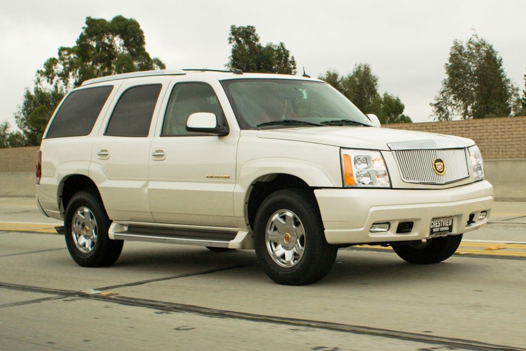 A white cadillac escalade suv driving on a highway.