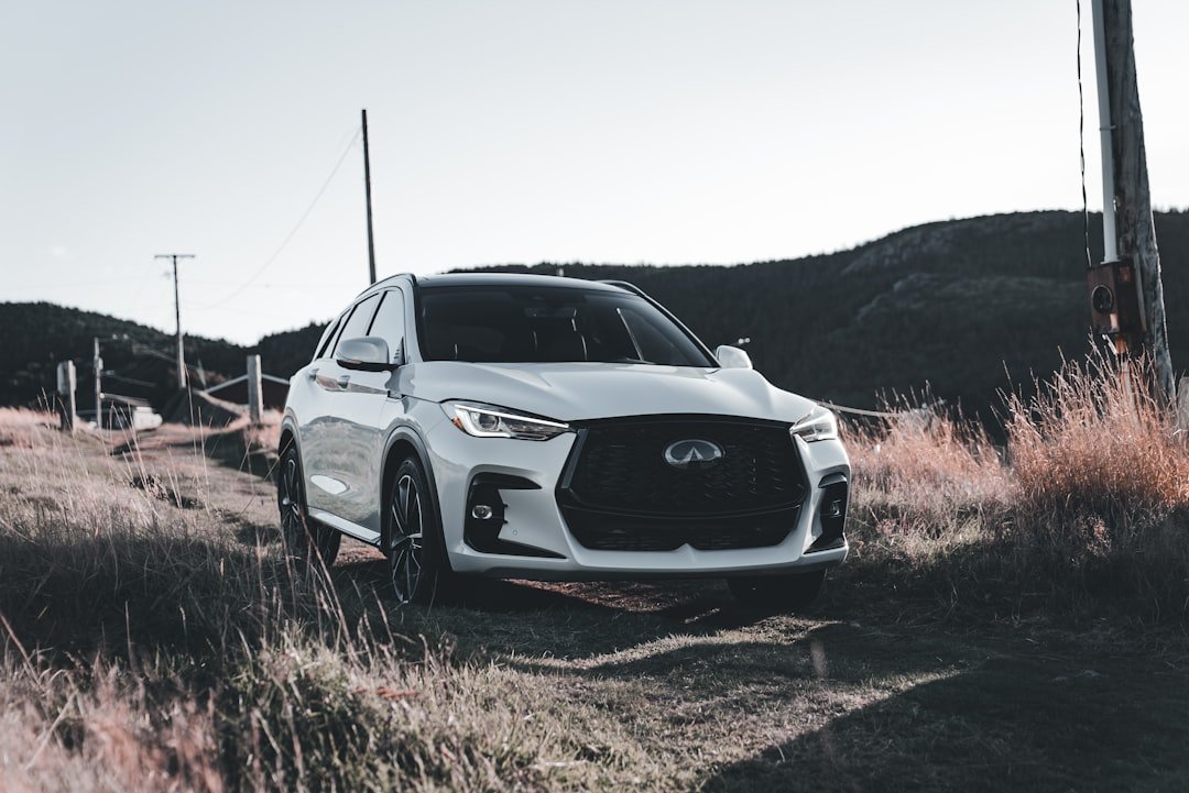 White suv parked on a dirt road near hills.