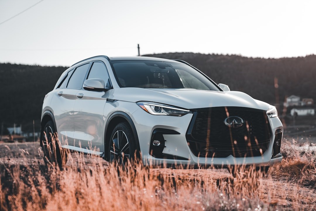 White car parked in a field at sunset.