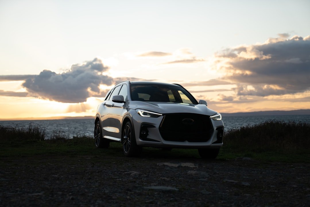 White suv parked by the ocean at sunset