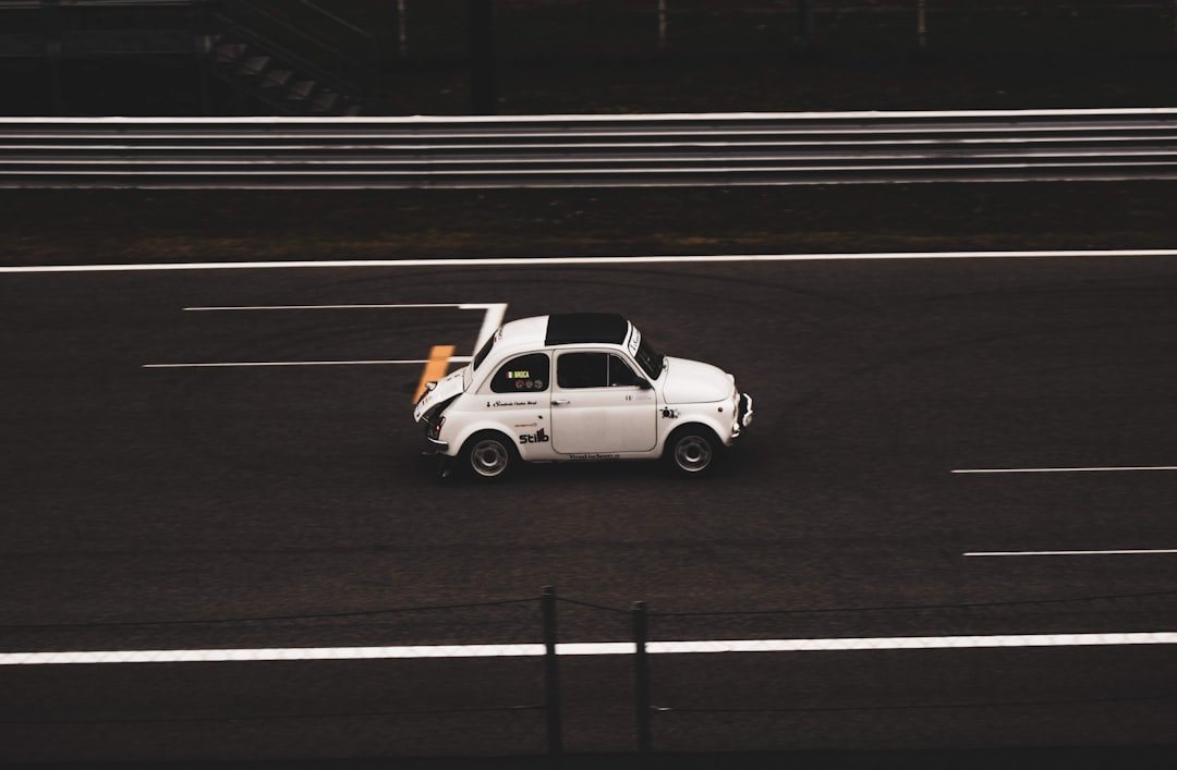 A small white car driving down a highway