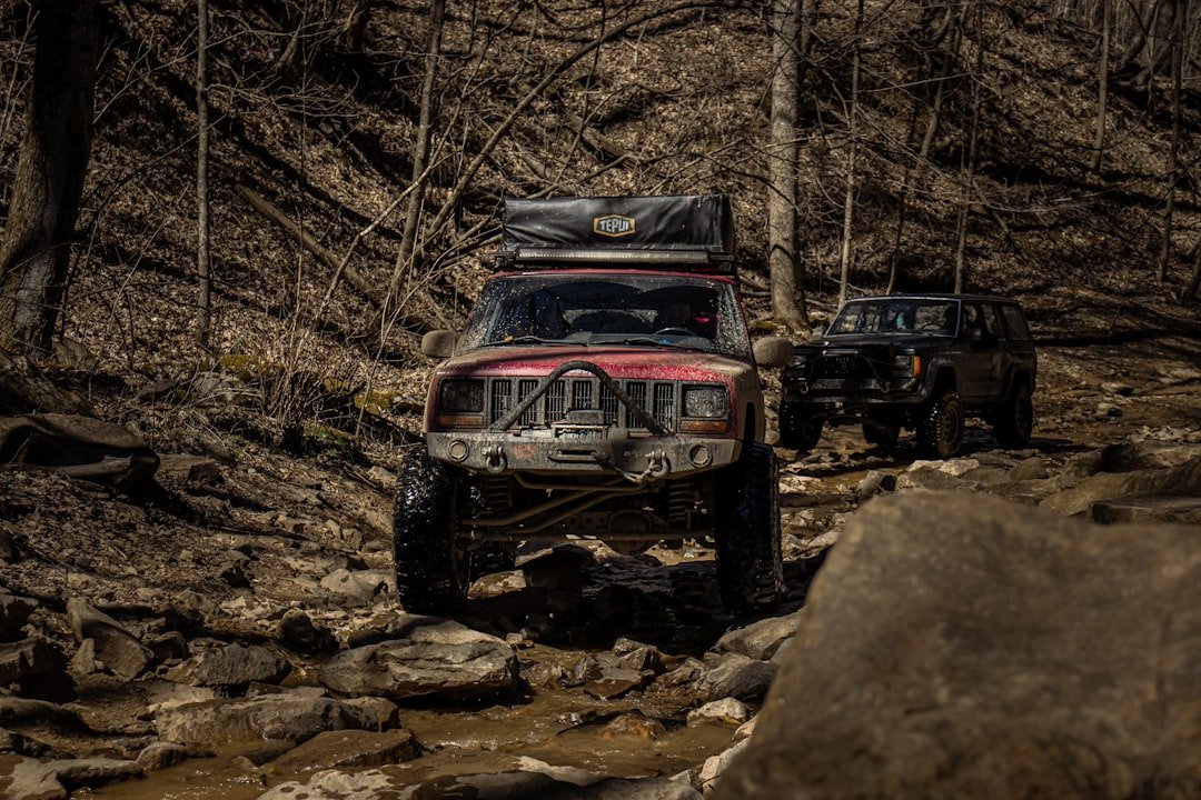 a couple of jeeps driving down a muddy road