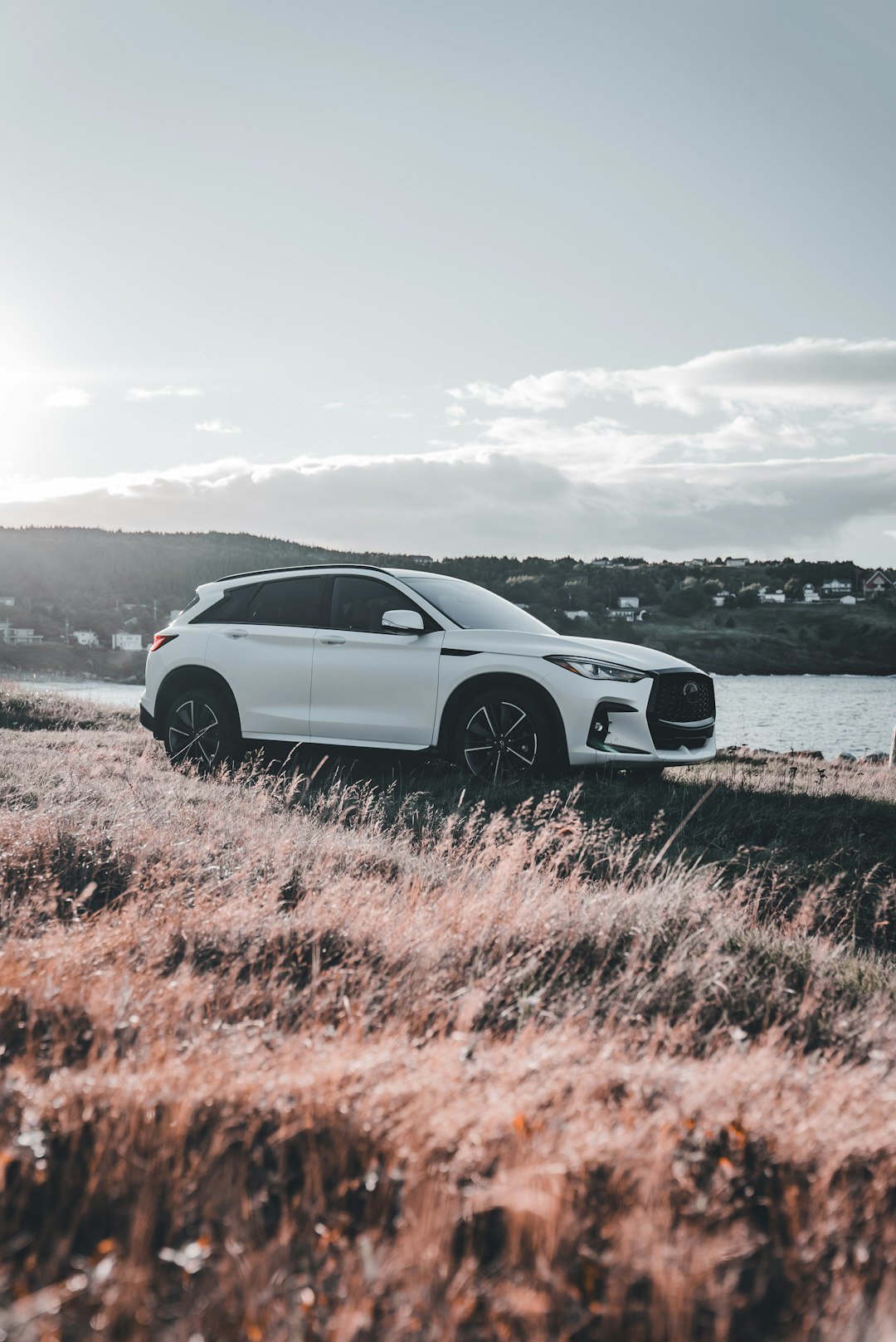 White suv parked on grassy hill overlooking water