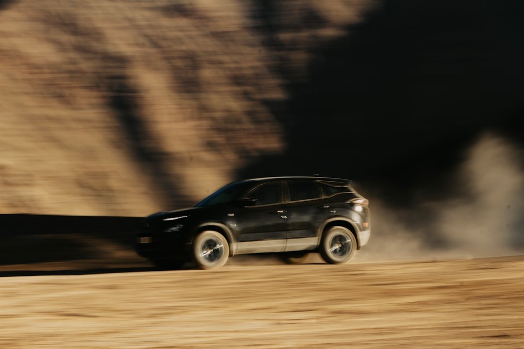 A black suv driving down a dirt road