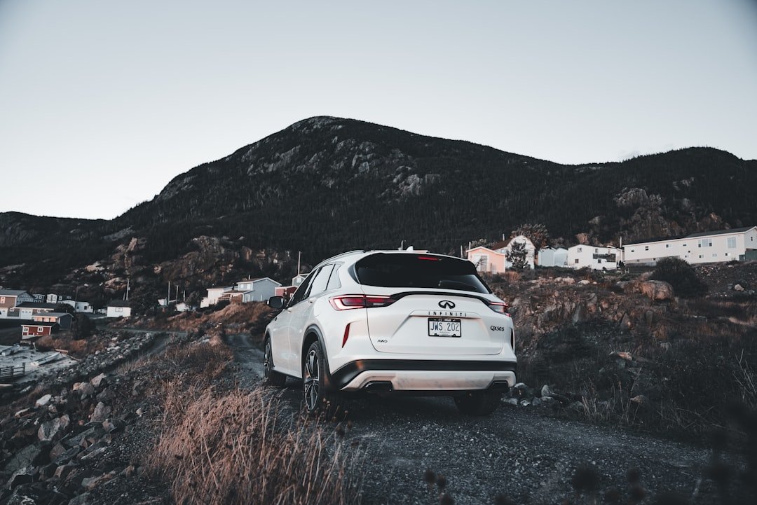 White suv parked on a gravel road near mountains.