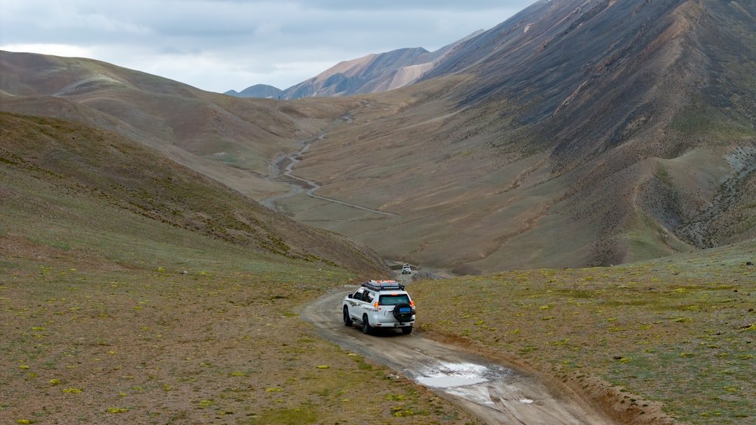 A car driving down a dirt road in the mountains