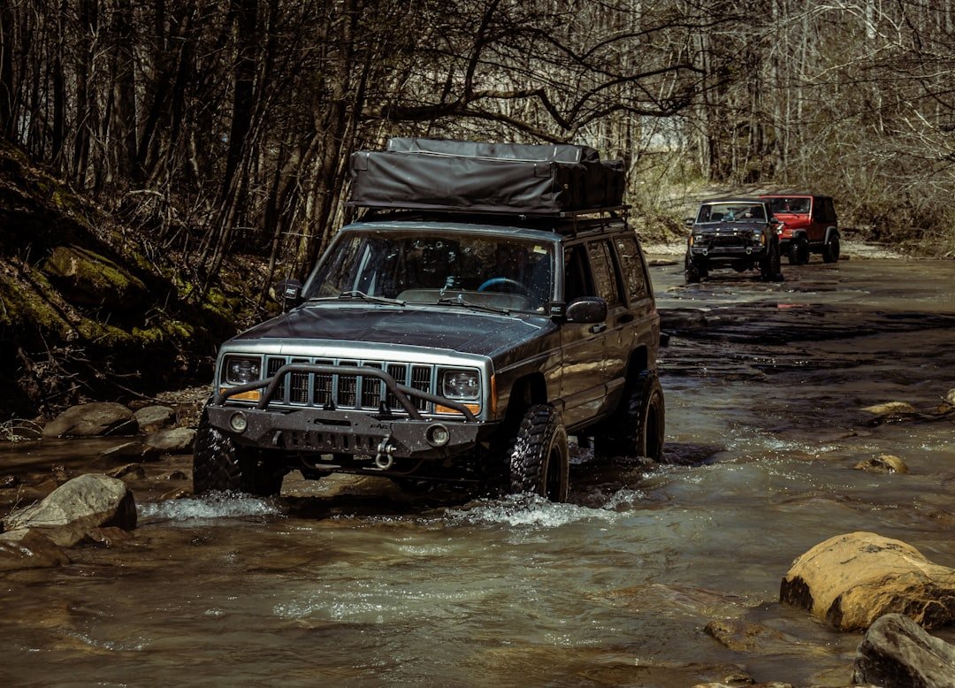 a jeep is driving through a stream in the woods