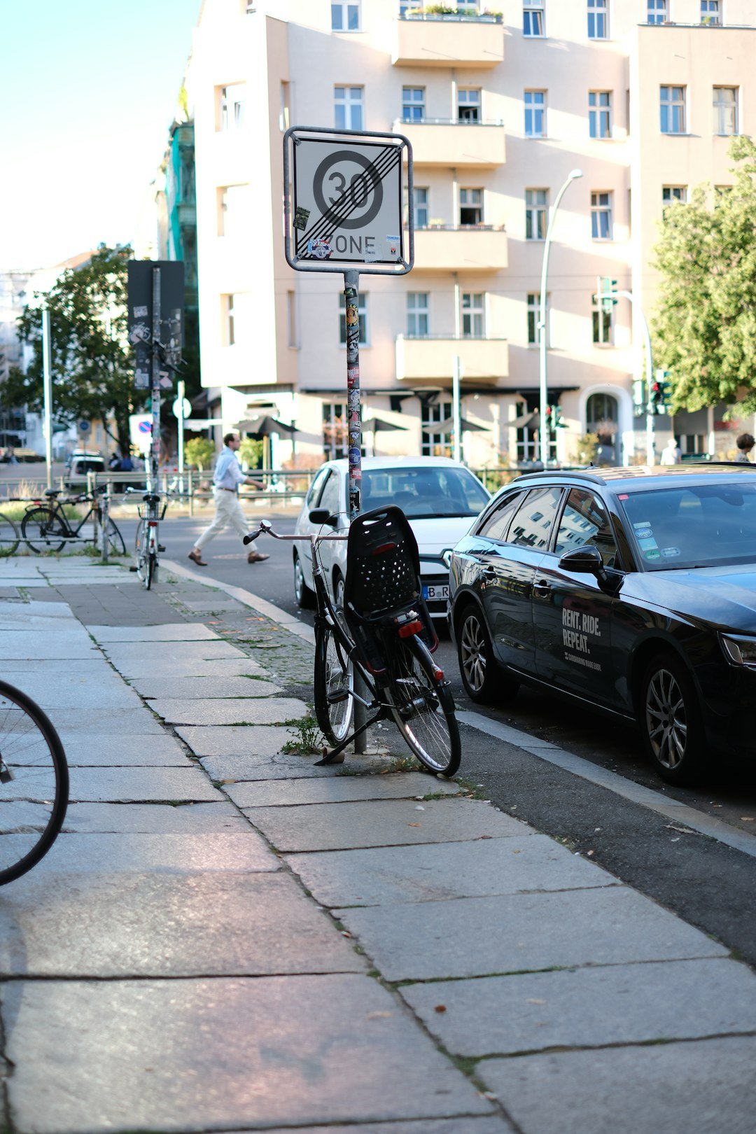 A car parked on the side of a street next to a bike rack