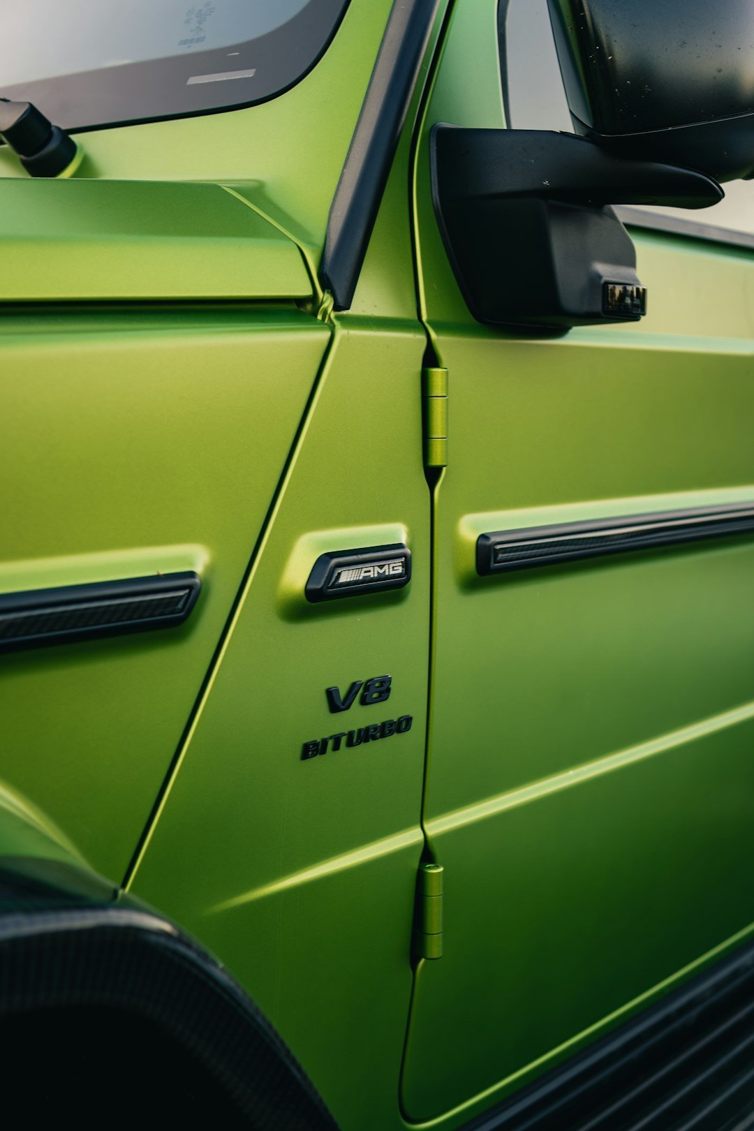 Close-up of a green car door with v8 biturbo emblem