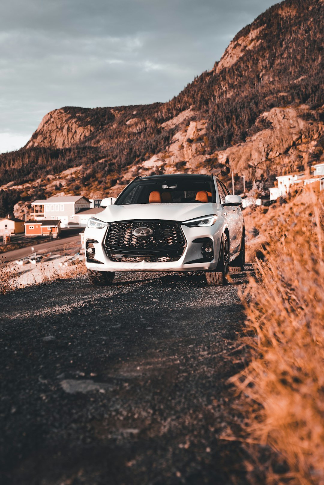 White suv parked on a gravel road near mountains.