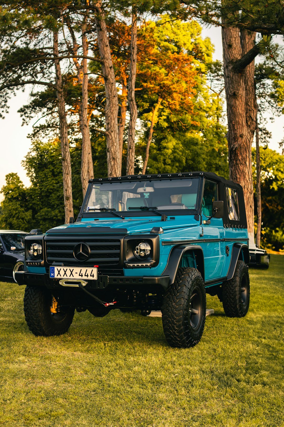 A blue mercedes-benz g-wagen parked on grass.