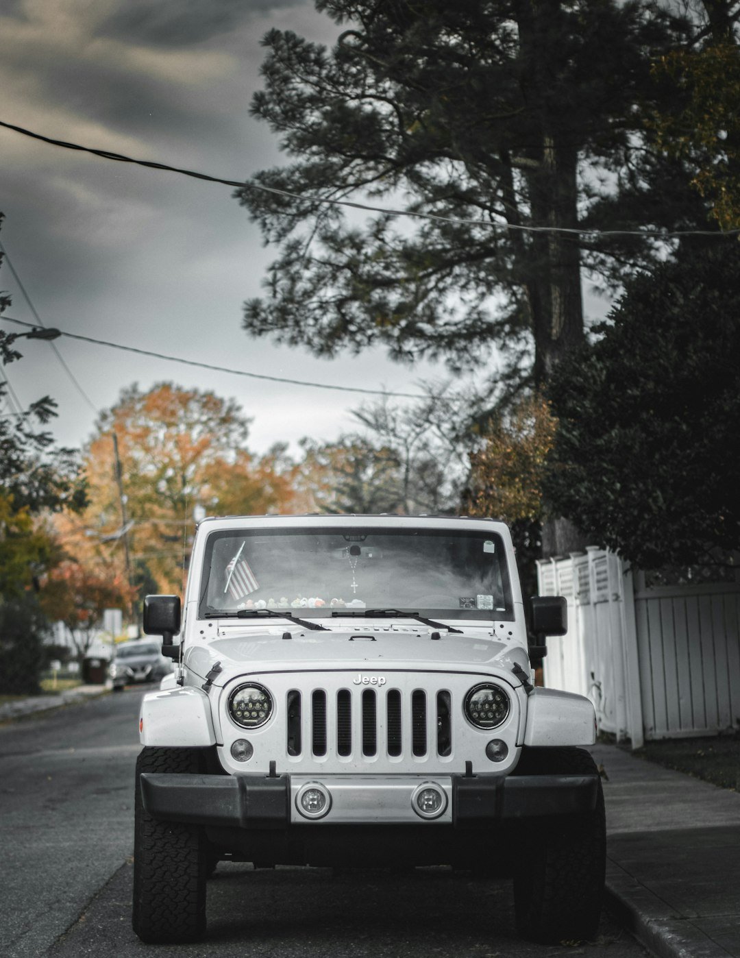 White jeep parked on a street with trees