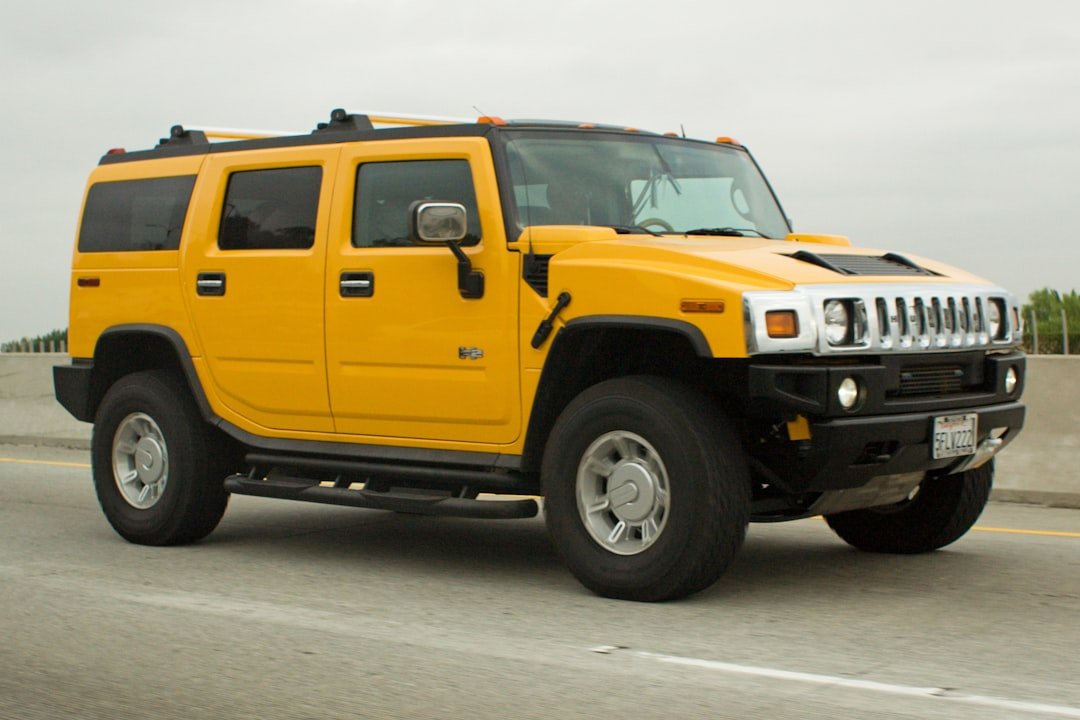 A bright yellow hummer h2 drives on a highway.