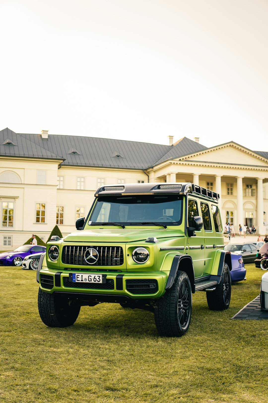 A lime green mercedes g-wagon parked on grass.