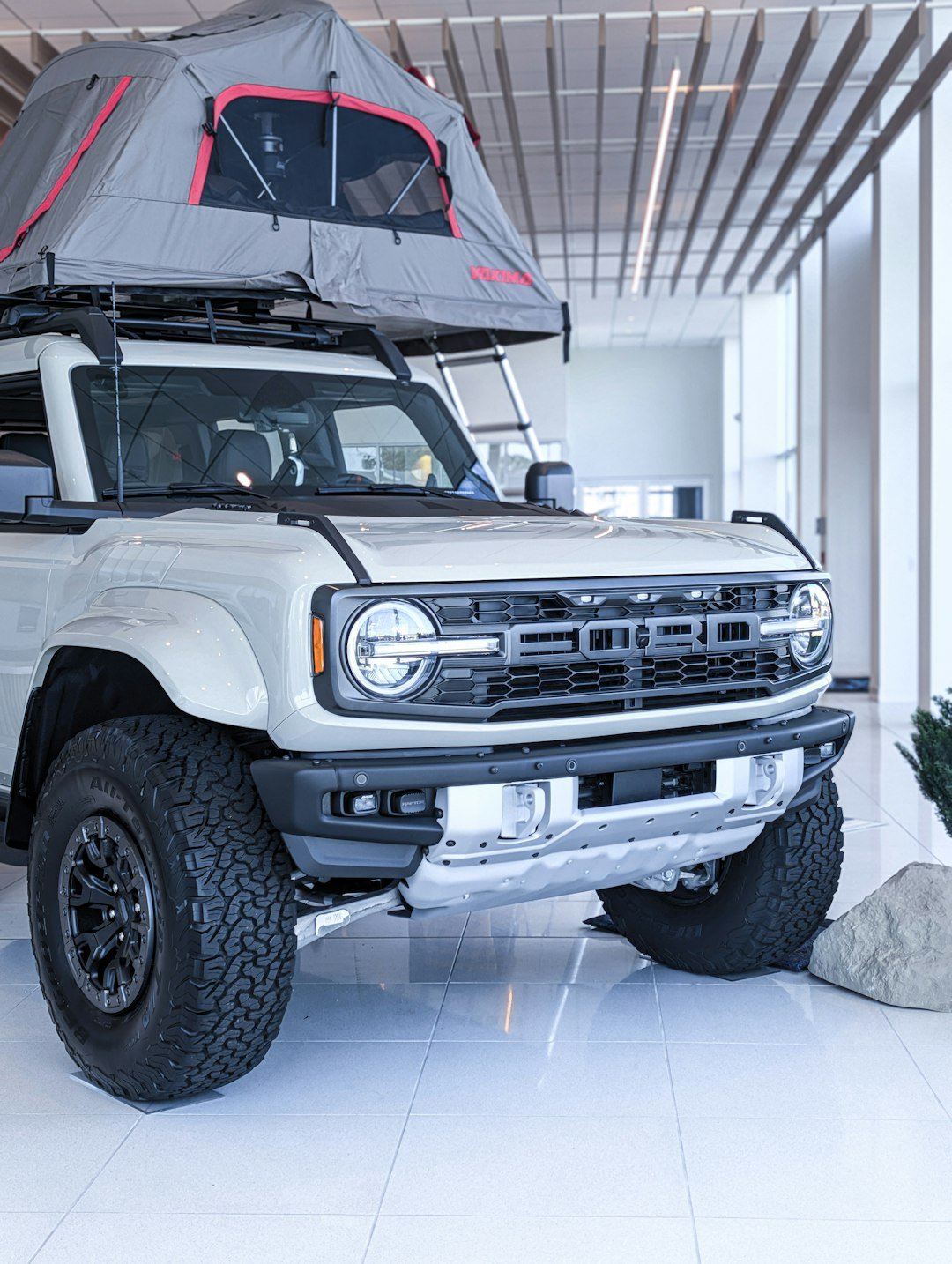 White suv with rooftop tent parked indoors.