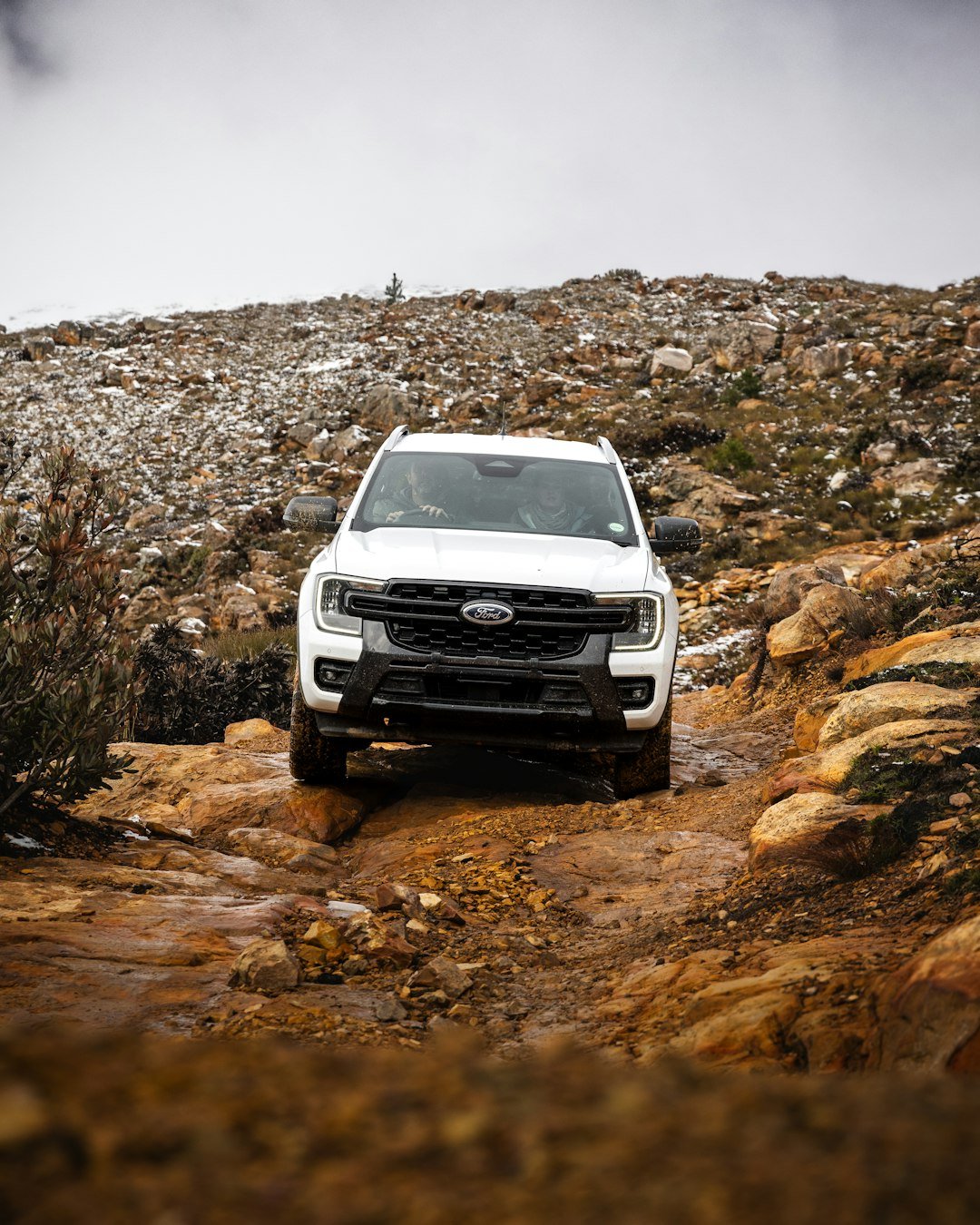 A white truck driving down a muddy road