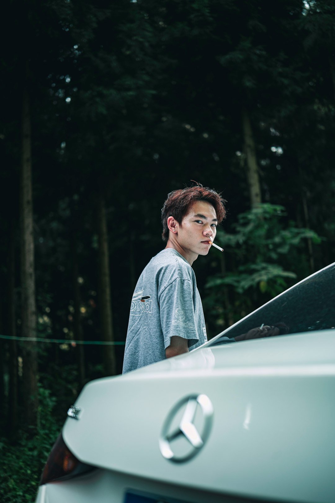 A young man standing next to a car