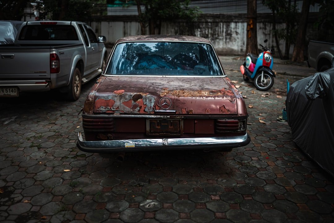 a rusted out car parked on a cobblestone street