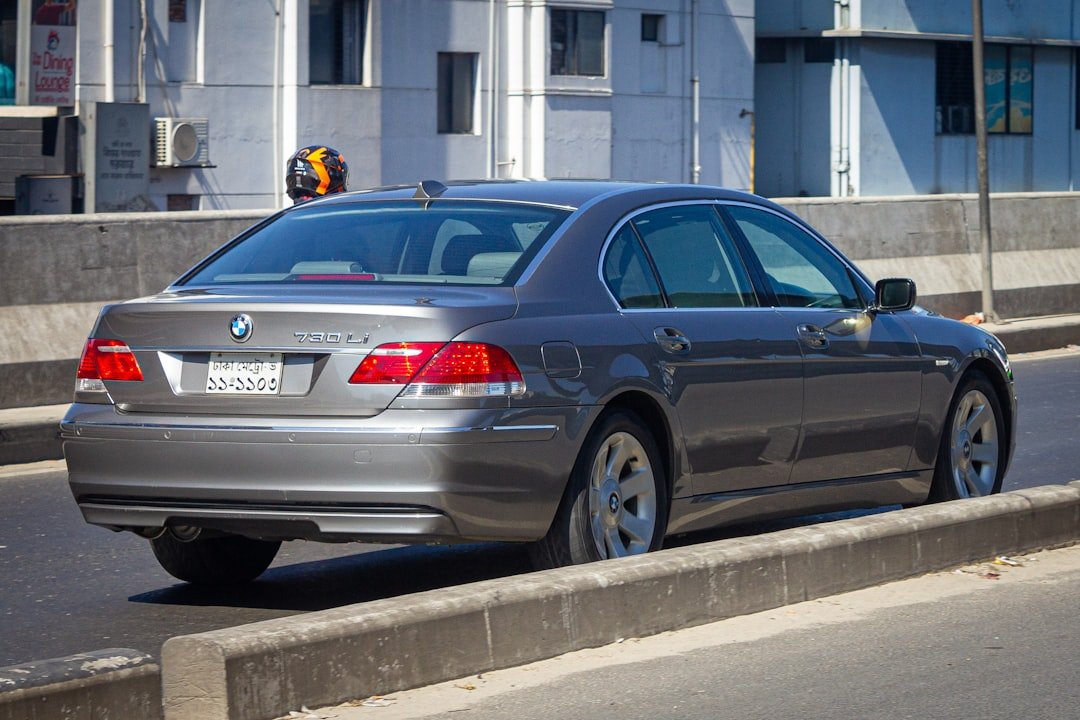 A silver car driving down a street next to tall buildings