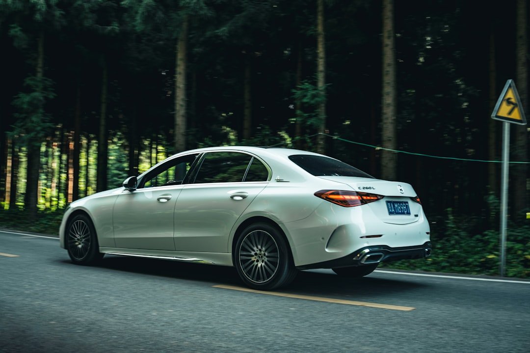 A white car driving down a road next to a forest