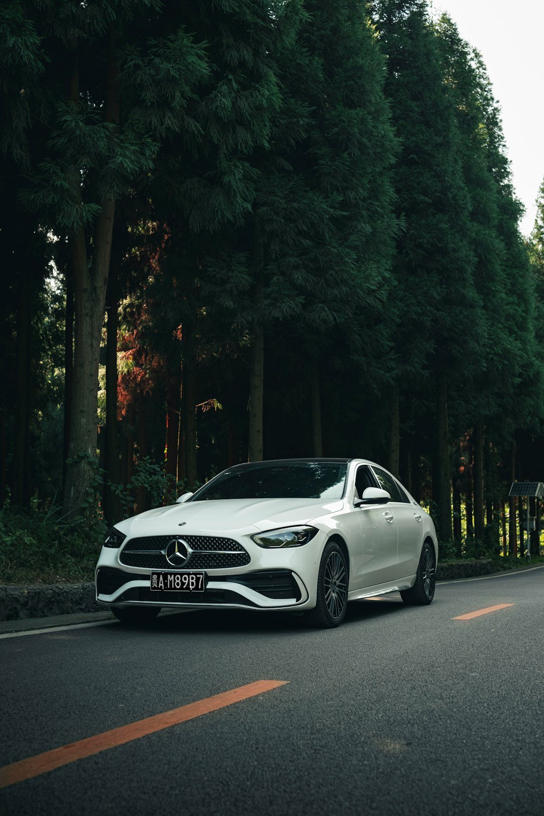 A white car is driving down the road