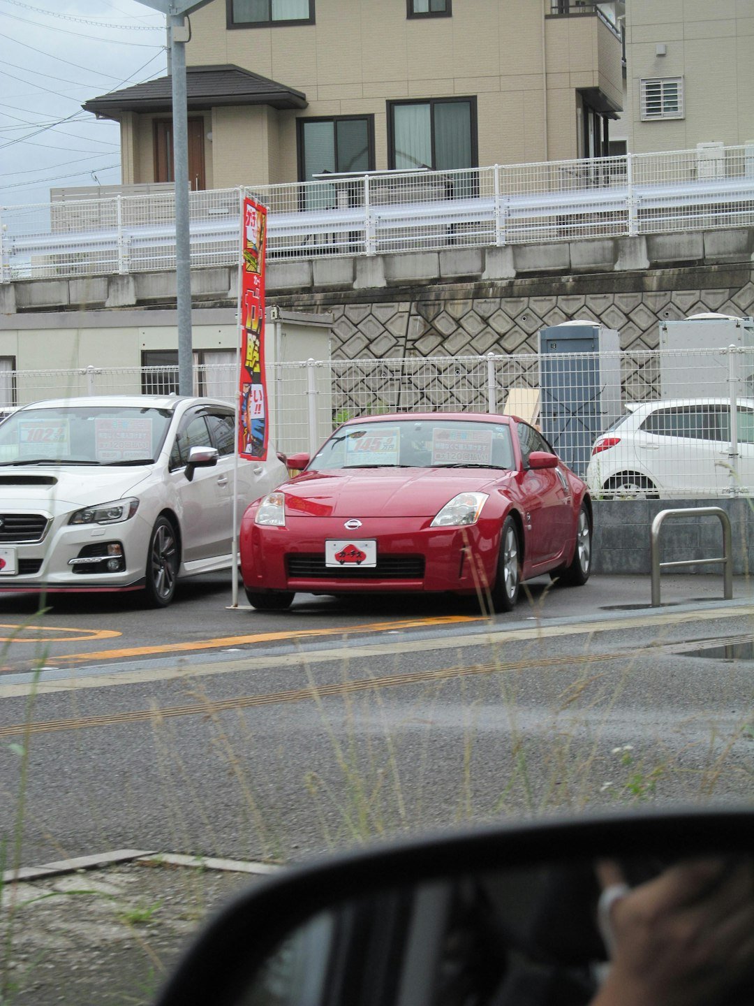 Red sports car parked between white cars.