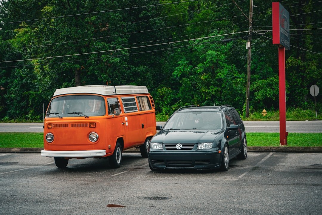 an orange van and a black car parked in a parking lot