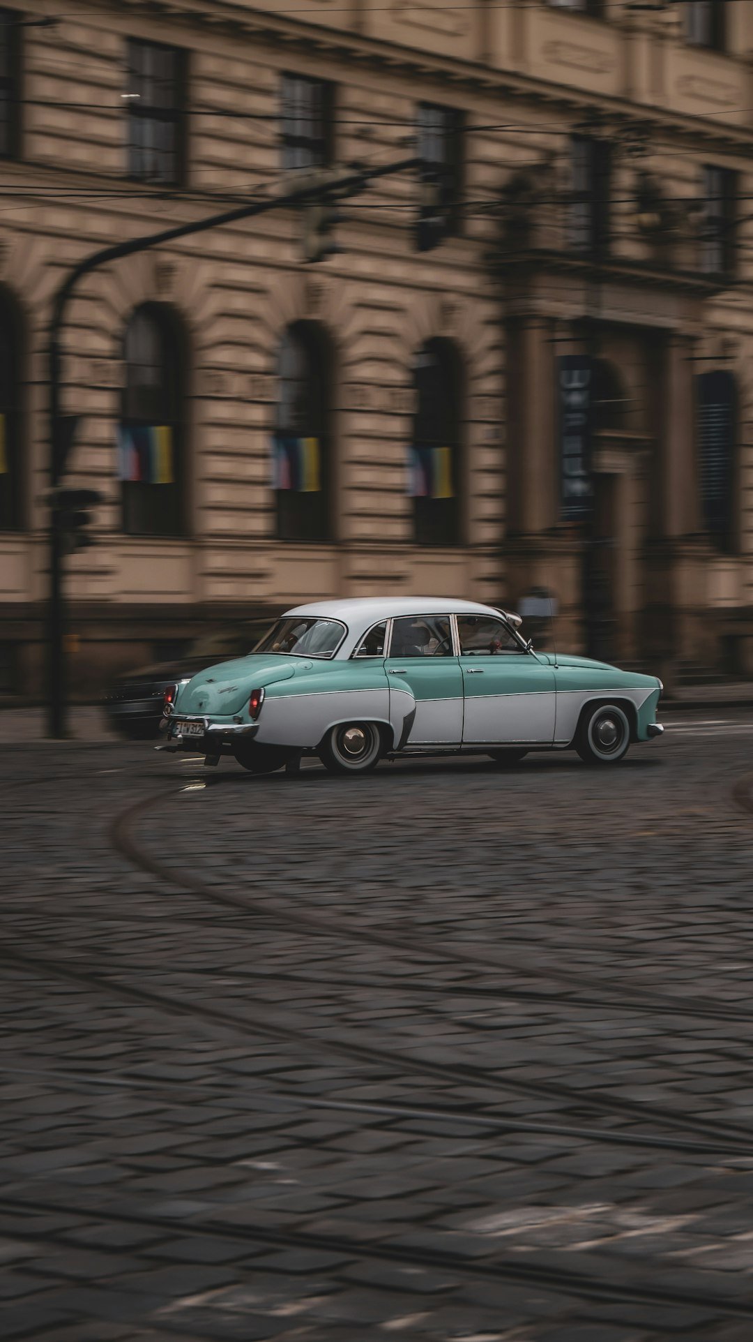 an old car is parked on a cobblestone street