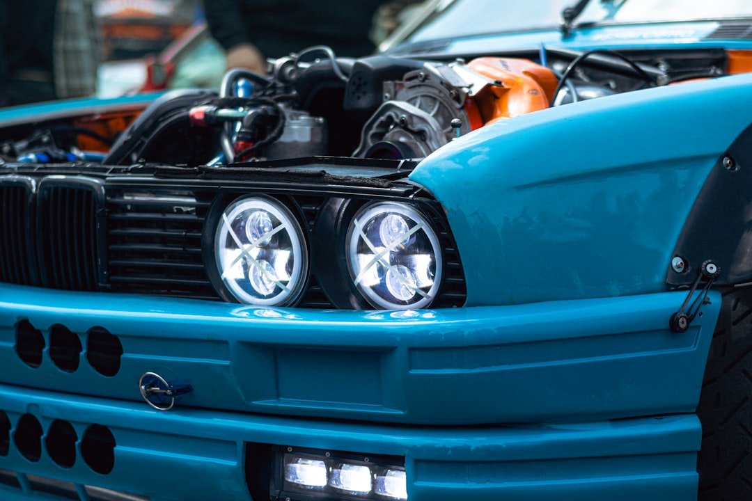 A bright blue car has its hood open.