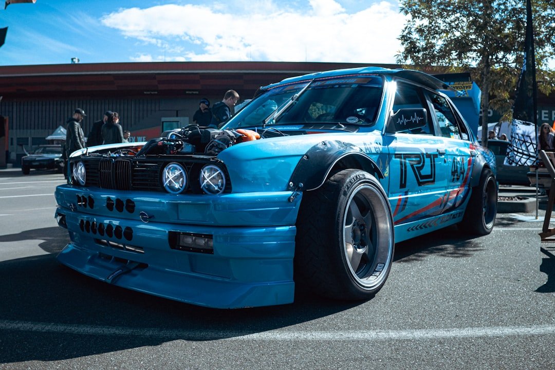 Blue, modified car is parked at an event.