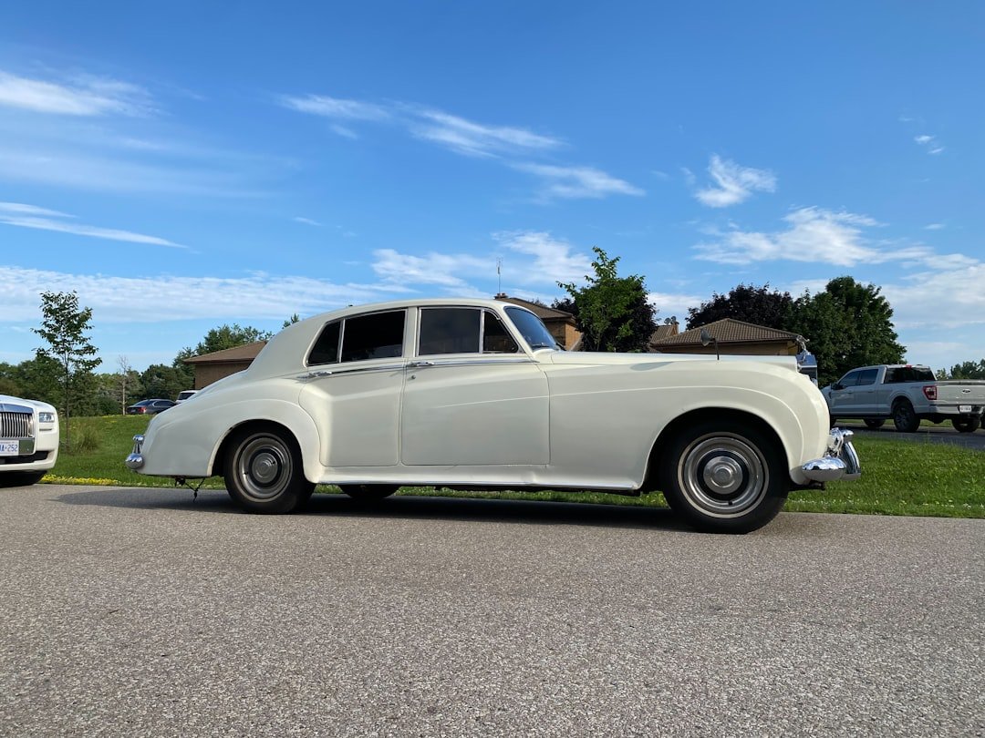 A classic white rolls-royce sedan parked outdoors.