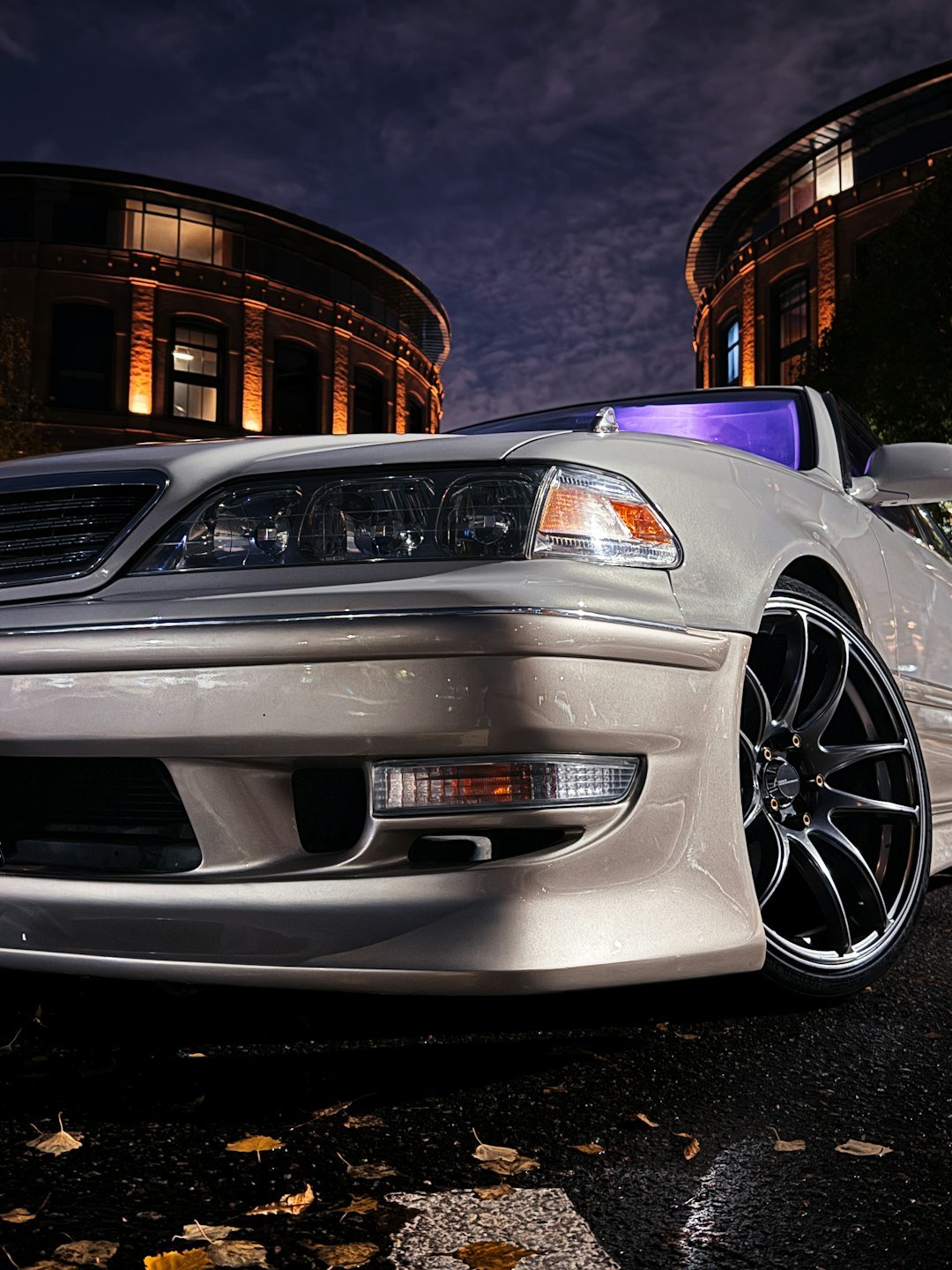 White luxury car parked on wet street at night