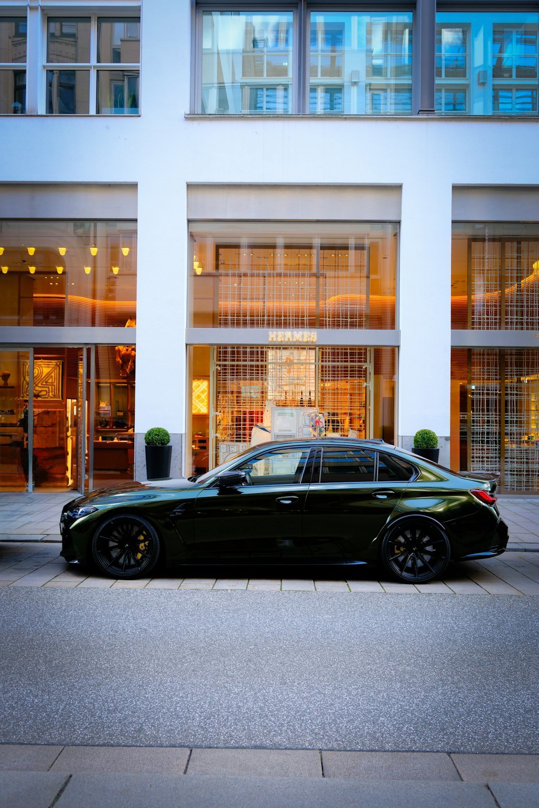 Dark luxury sedan parked in front of modern building