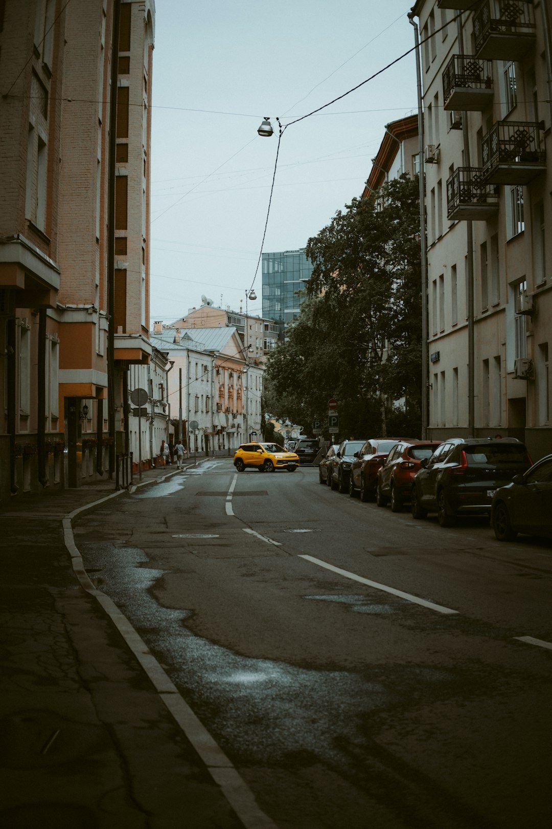 A yellow car drives down a city street.