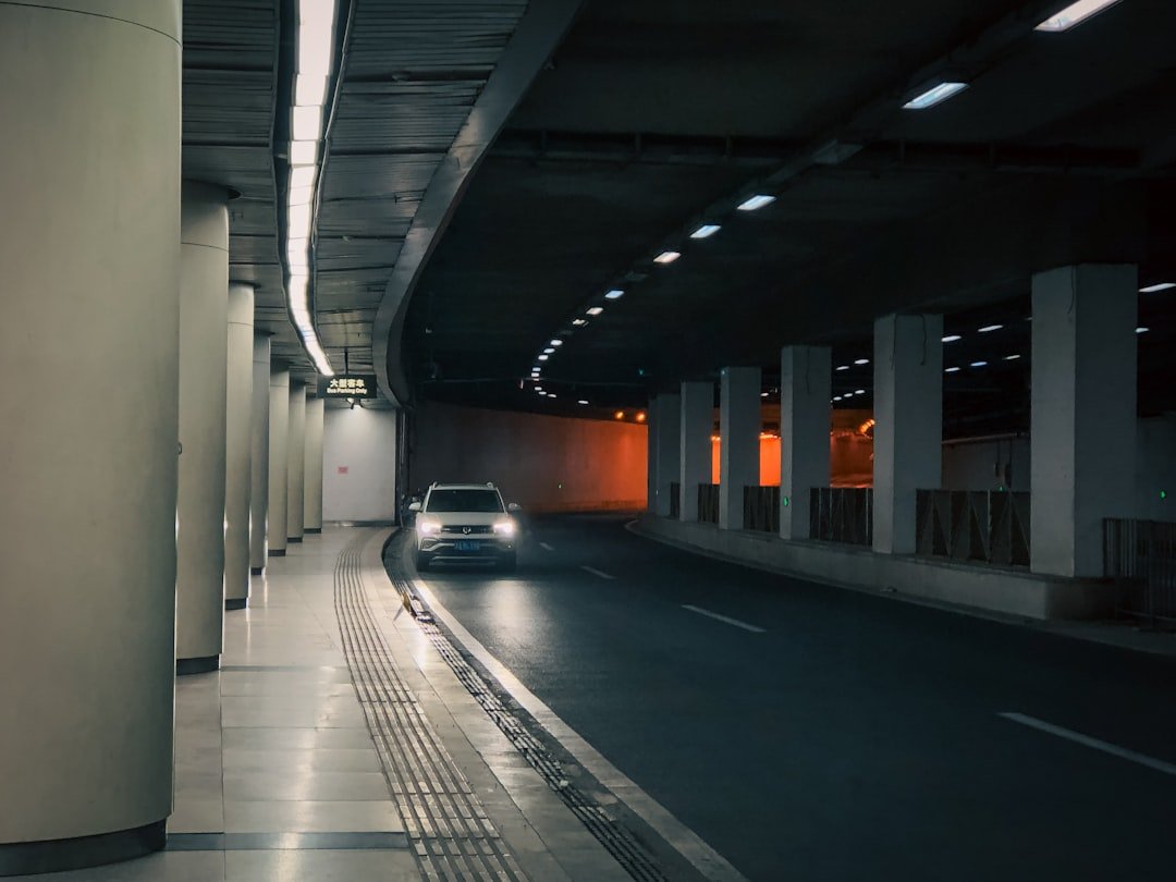 A car drives through a dark and lit tunnel.