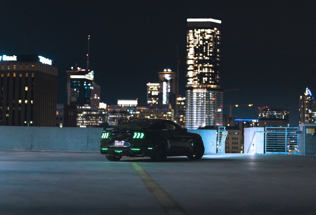a black sports car driving down a city street at night