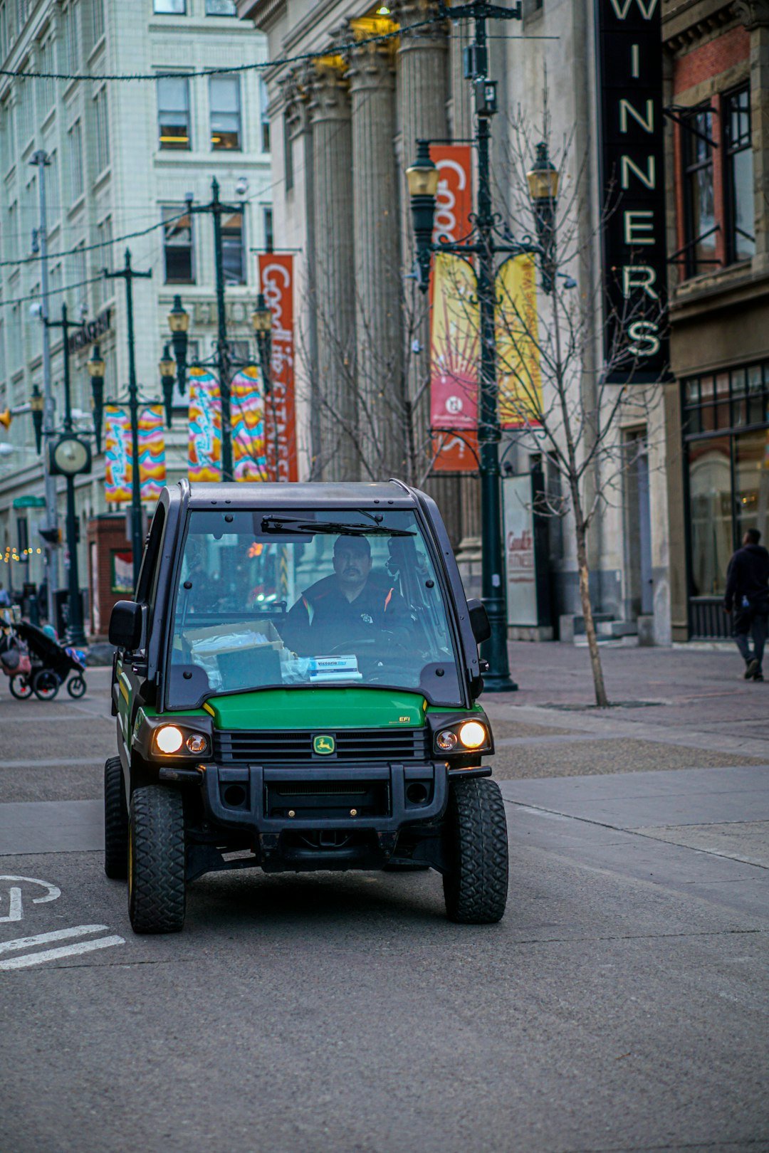 Green utility vehicle driving on a city street.