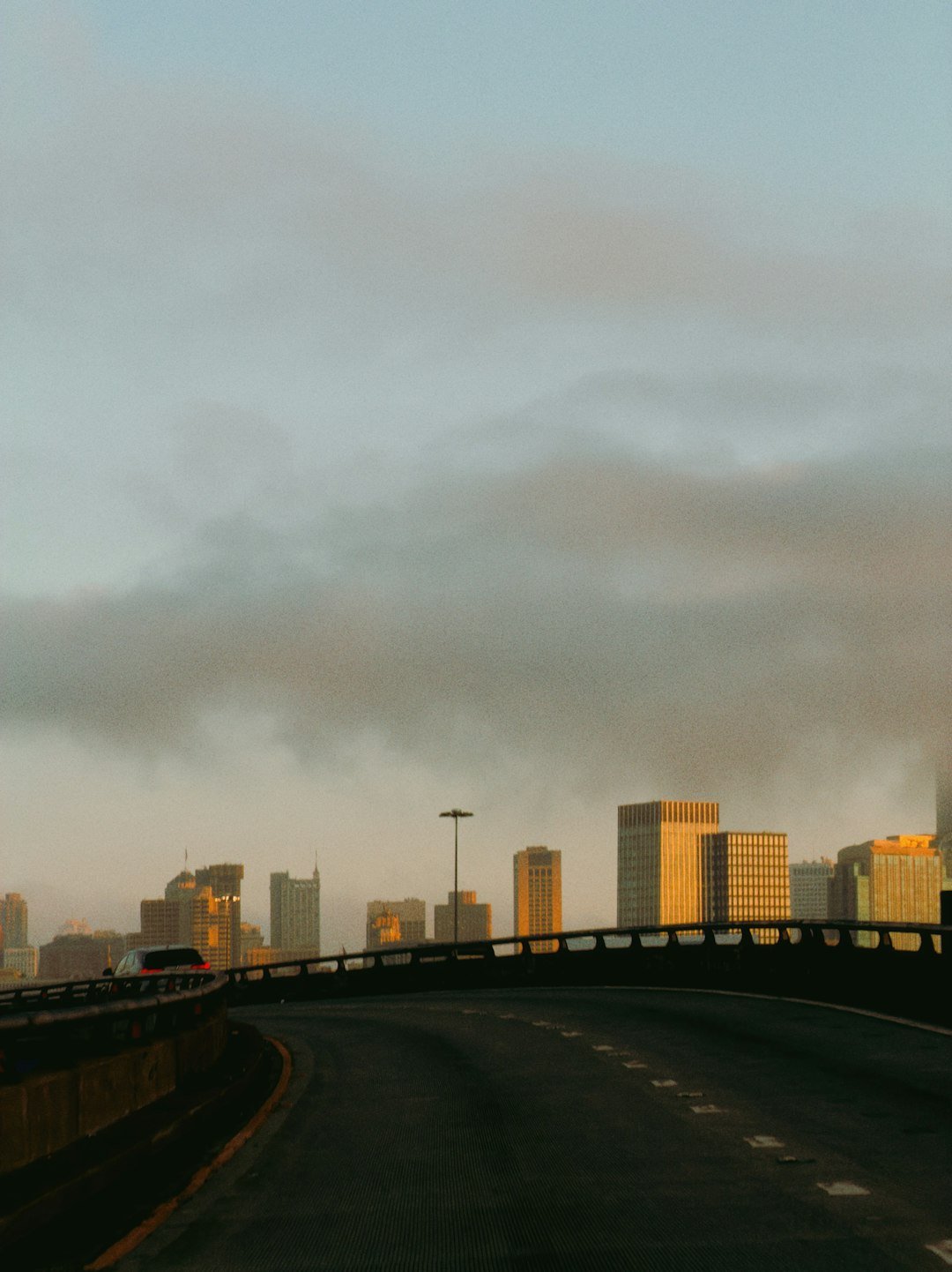 City skyline at sunrise with a highway in foreground.