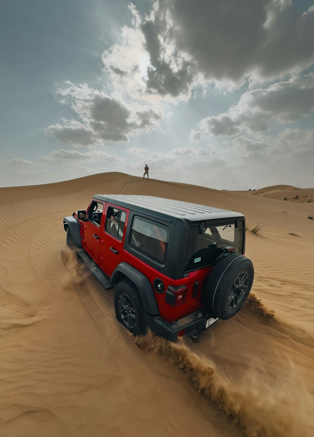 A red jeep driving through the desert