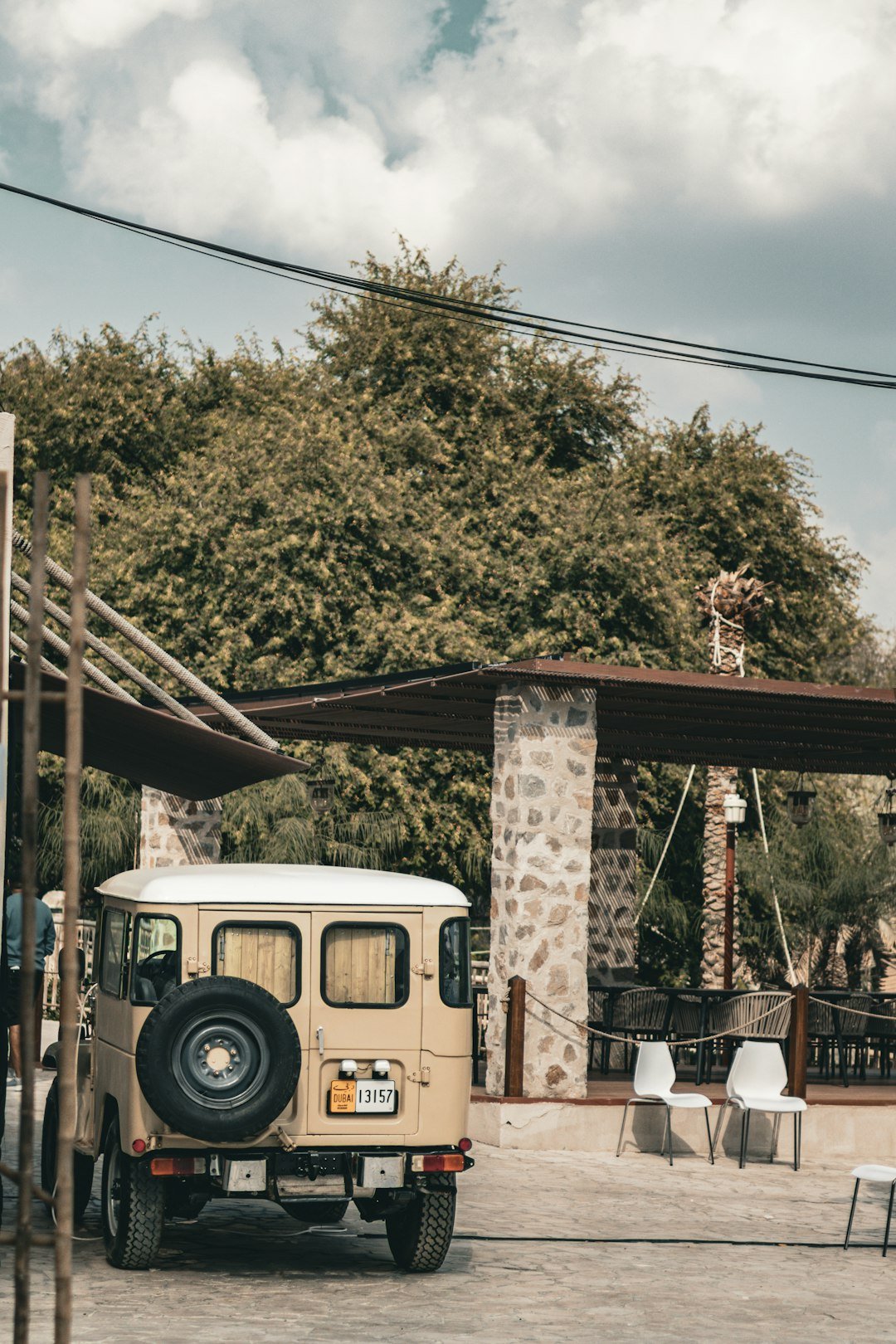 A vintage jeep parked outside a shaded outdoor seating area.
