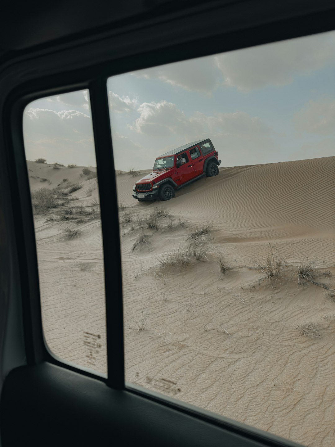 A red truck driving through a sandy desert