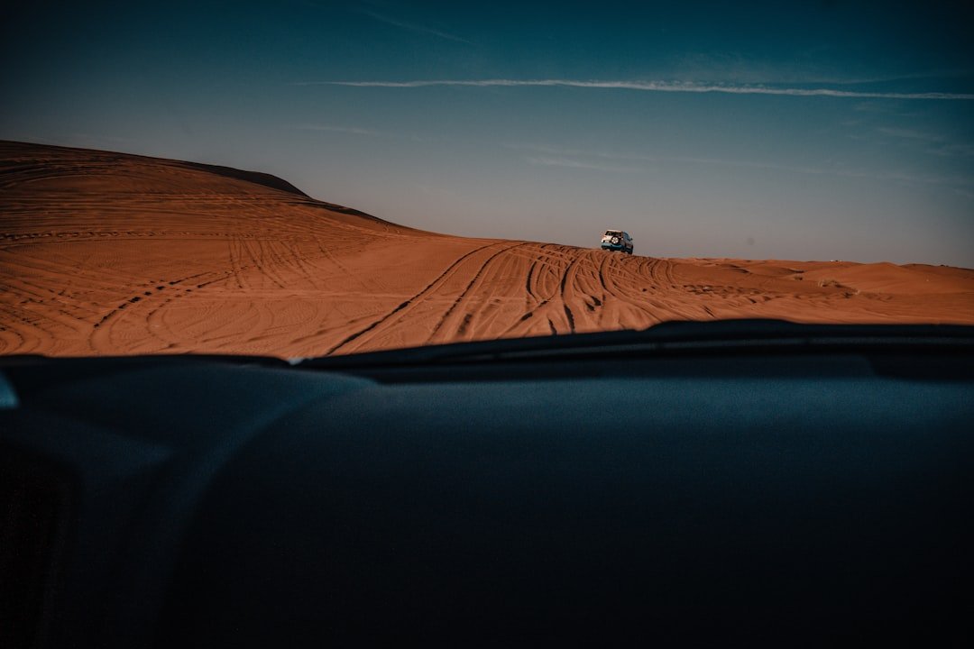 a car driving down a sandy road in the desert