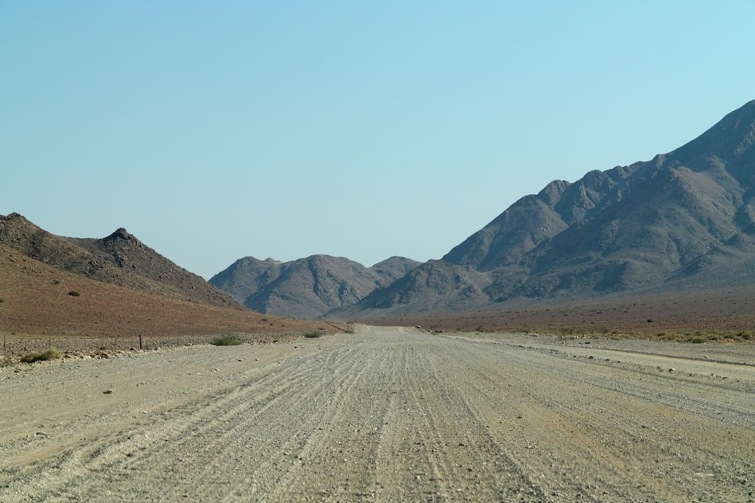 A dirt road with mountains in the background