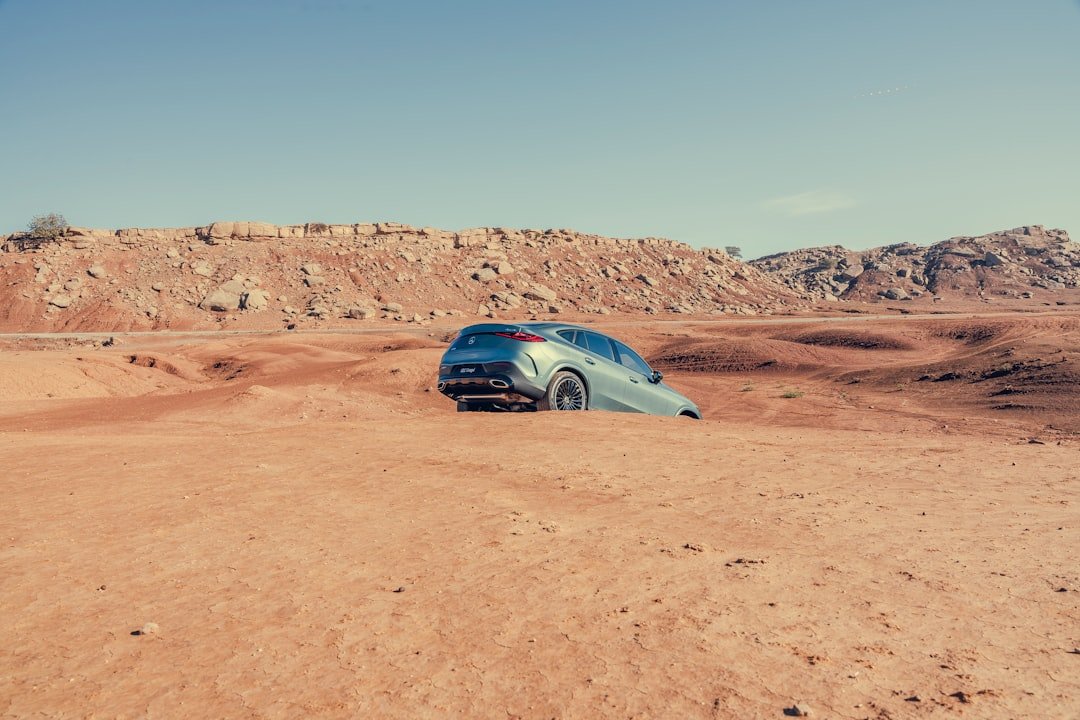 Silver suv stuck in a dry, sandy landscape.