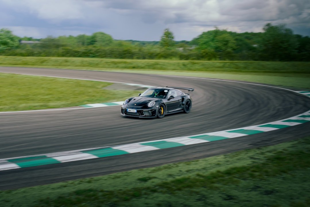 A black sports car driving on a race track.