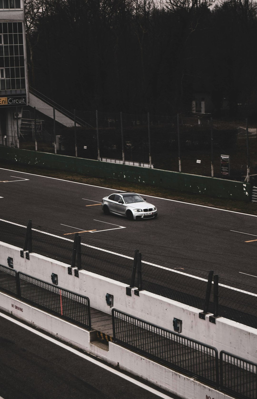 A white car driving down a highway next to a tall building