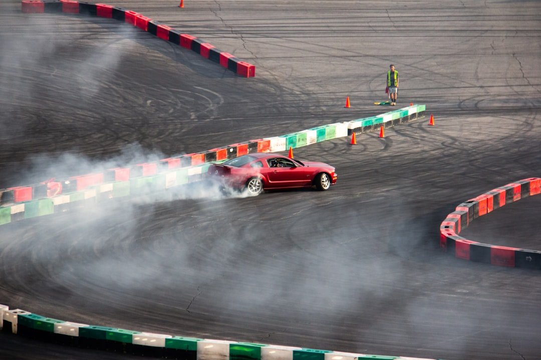 a red car driving around a track with smoke coming out of it