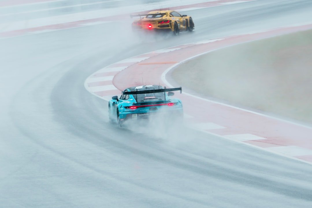 Race cars speed through wet track during competition.