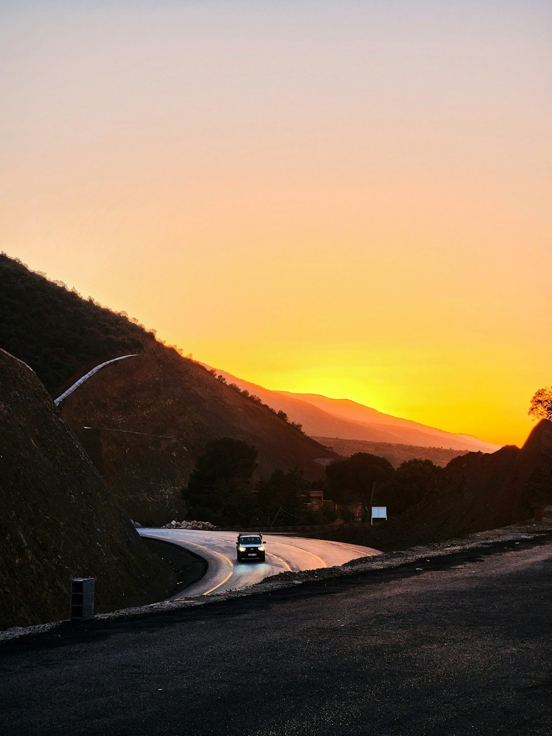The sun is setting over a mountain road