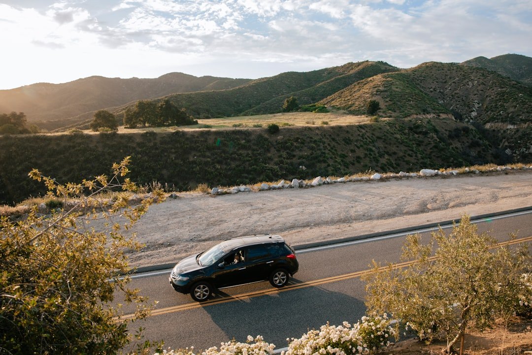a car driving down a road with mountains in the background